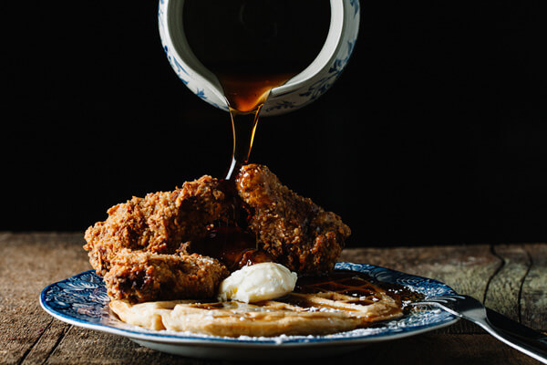 chicken and waffles with syrup being poured over the top